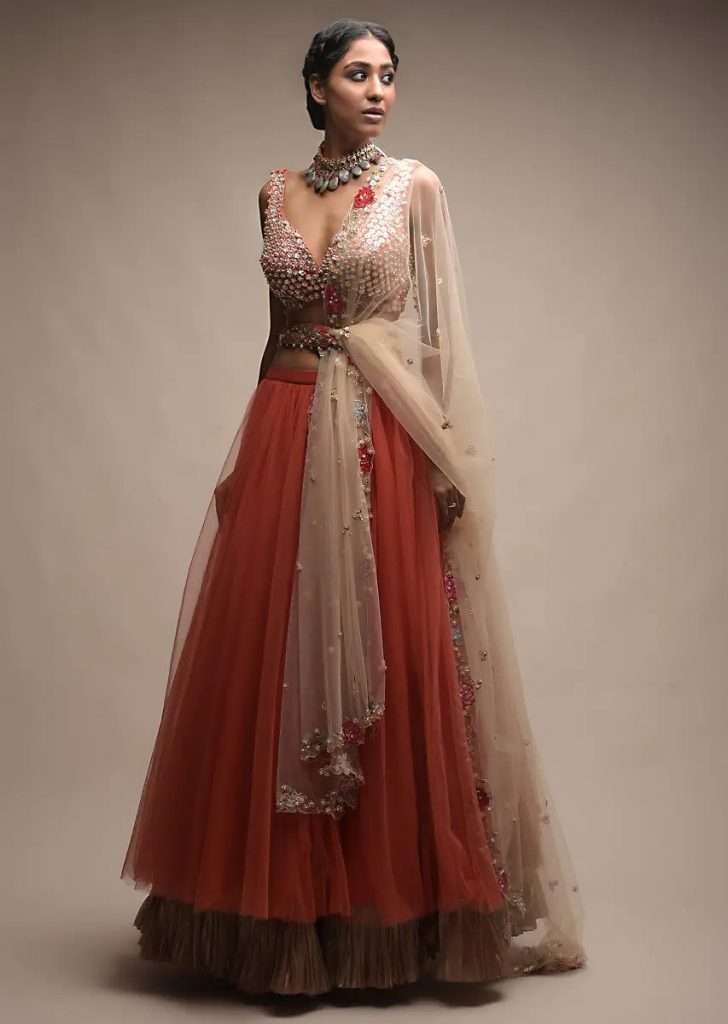 A Women Posing for Photo wearing Coral Lehenga In Net With Pleated Frill And Sequins Embellished Crop Top