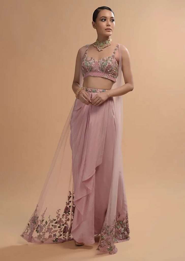 A Women Posing For Photo wearing Icy Pink Draped Skirt And Crop Top Set With Long Jacket And 3D Flower Embroidery