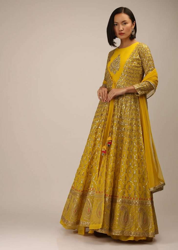 A photographed woman wearing a mustard floor length jacket suit with zari and sequin embroidered Moroccan mesh