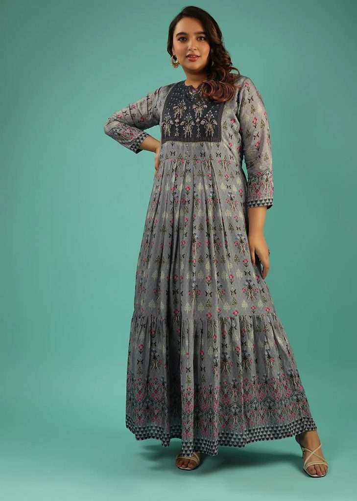 A woman poses for a photo in a cloud gray cotton silk tunic with embroidered bodice and printed floral and bird motifs.