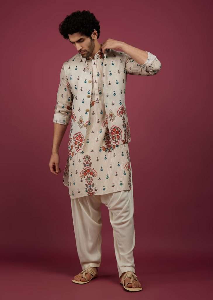 A man poses for a photo wearing a birch white silk printed kurta set with a jacket in sequins and zari work.