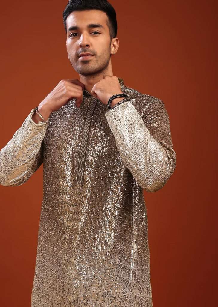 A man poses for a picture wearing a Kalki festive kurta set in a gradient shade of silver and brown with full sequin embroidery