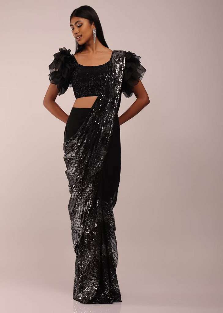A woman wearing noir black ready pleated saree with ruffled sleeves blouse in stones and sequins embroidery is photographed