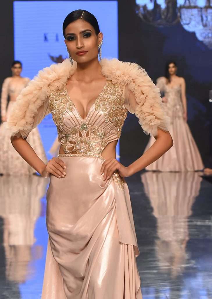 A woman is photographed wearing Kalki Festive Silver Pink Victorian Gown in Satin Milano with Ruffle Sleeves and Cowl Drape