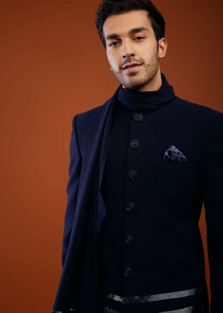 A man wearing a navy blue jodhpuri sherwani set in imported suiting fabric poses for a photo