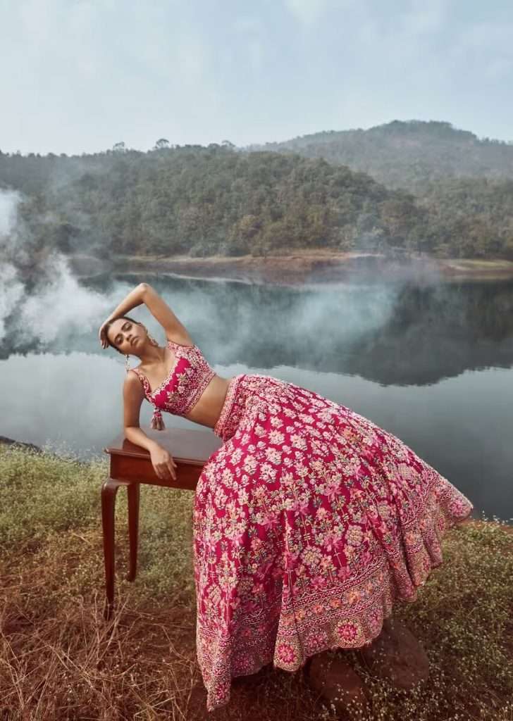 A woman is photographed in colorful silk wearing queen pink lehenga choli with colorful silk and cut dana embroidery summer flowers and detailed border