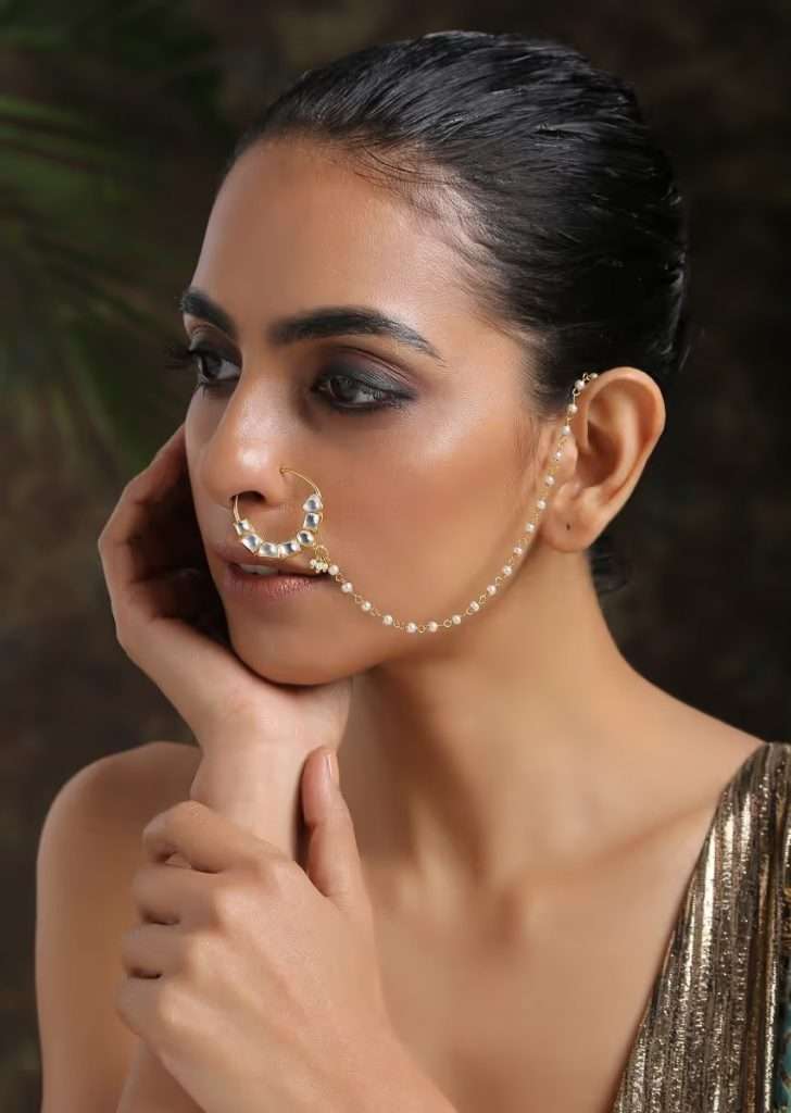 A Women Posing for Photo Wearing Gold Plated Nose Ring Intricately Put Together With Fascinating Shapes Of Kundan And Shell Pearl Detailing By Paisley Pop