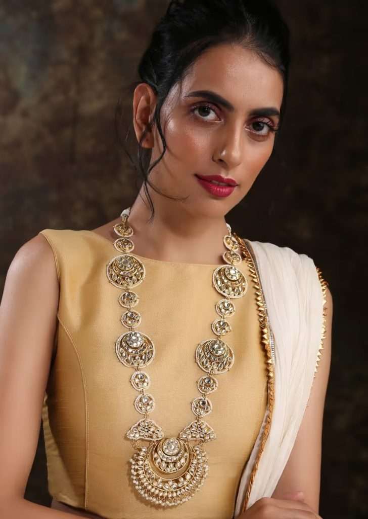 A Women Posing for Photo Wearing Gold Plated Royal Kundan Necklace Handcrafted In An Elegant Design With Dangling Pearls By Paisley Pop