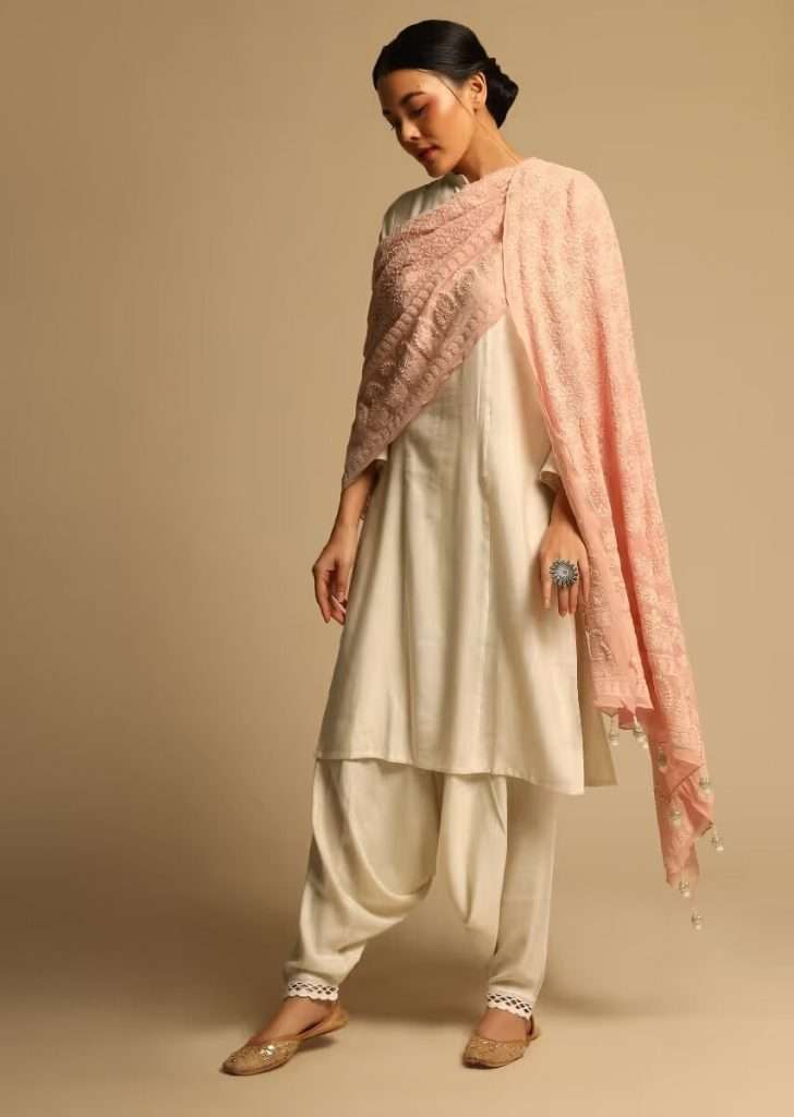 A woman posing for a photo wearing a white kurta set without a dupatta in cowl pants