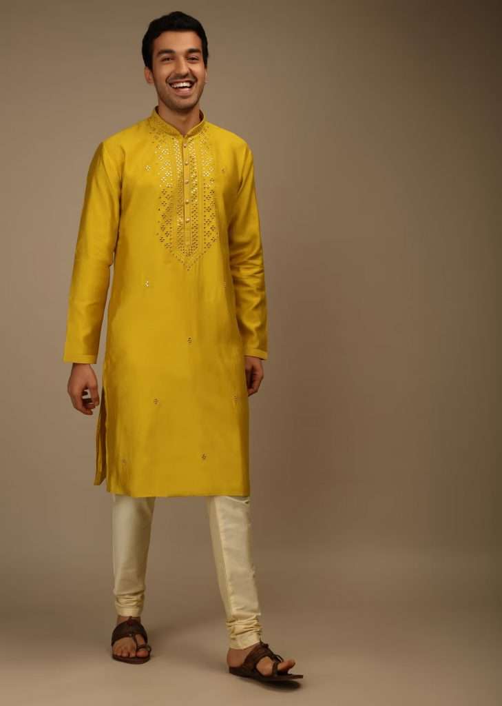 A man wearing sulfur yellow kurta set in silk with silk and mirror abla embroidered yoke design is posing for a photo