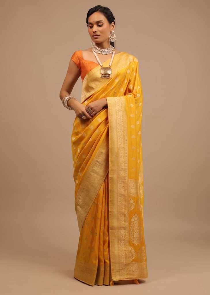 Women posing for photo wearing Marigold Yellow Saree In Dola Silk With Woven Buttis And Floral Pallu Weave